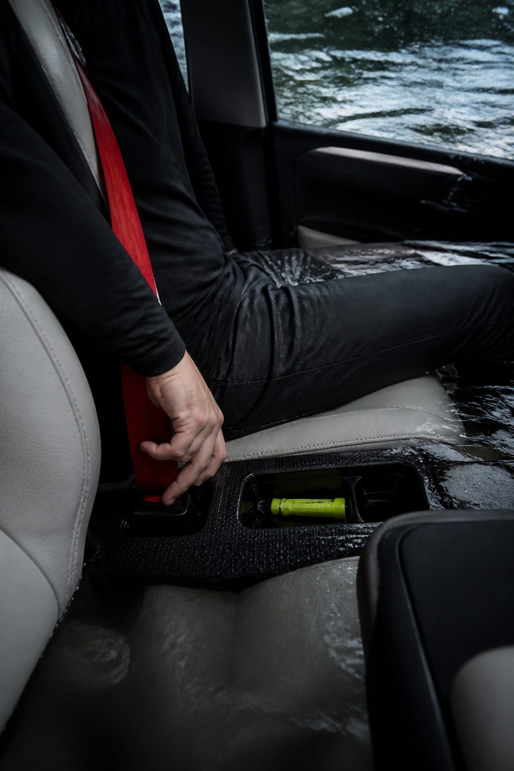 How to Escape a Sinking Car: 5 Steps That Save Lives in 2026 2 A hand reaching for a seatbelt release against a wet car interior.