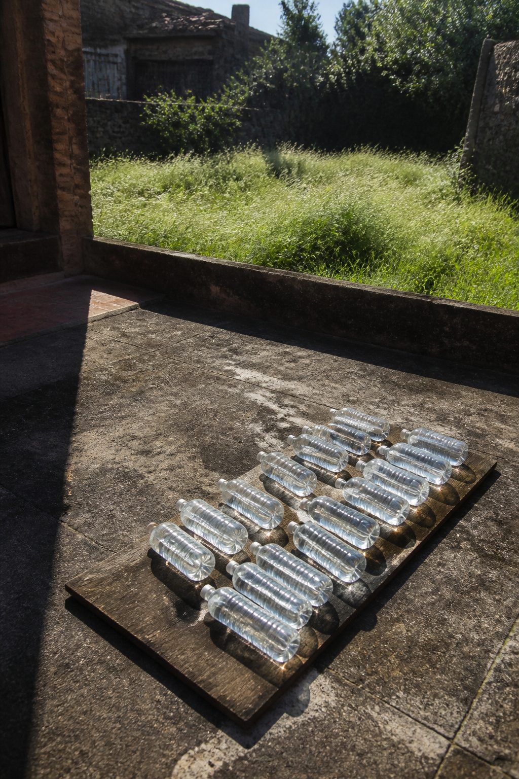 Flat bottles of water placed on a dark surface in sunlight.