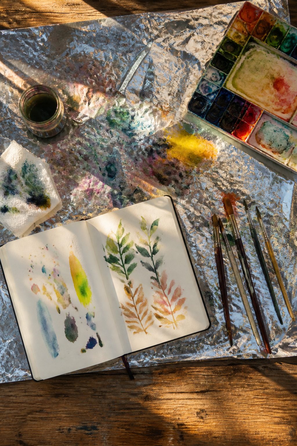 Mylar Blanket Uses: 38 Practical Ideas for Emergencies & Daily Life (2026) 39 A mylar blanket under a watercolor painting setup on a table.