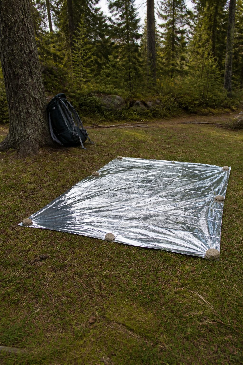 Mylar Blanket Uses: 38 Practical Ideas for Emergencies & Daily Life (2026) 3 An unfolded mylar blanket used as a ground tarp on rough terrain.