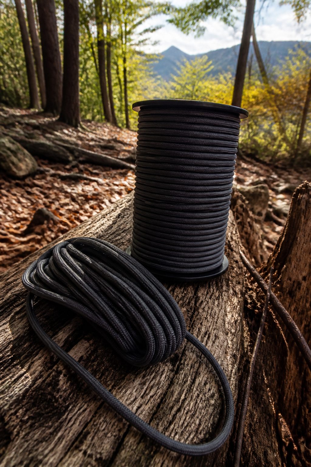 Heavy-duty Type IV paracord spool on a fallen log with leaves.
