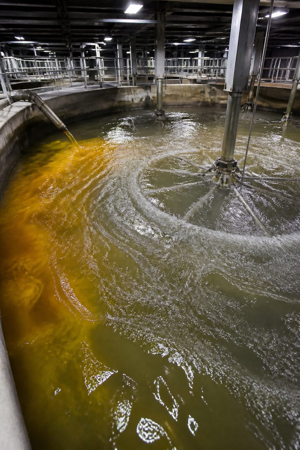 A large coagulation tank filled with murky water and mechanical paddles.