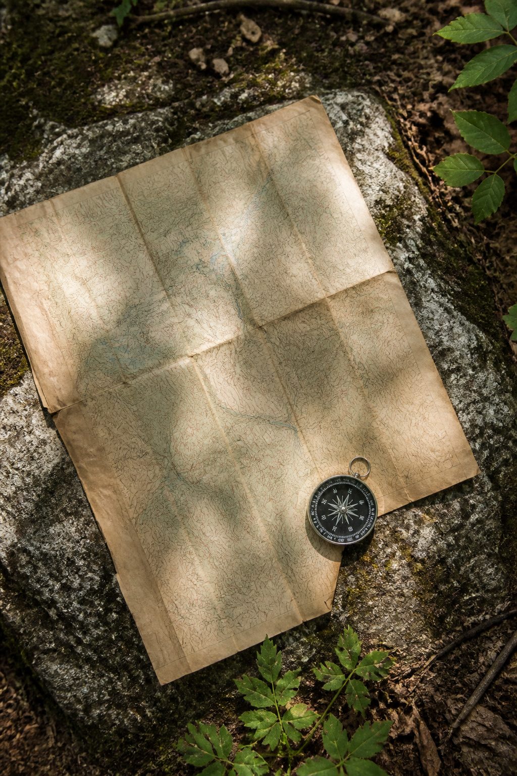 10 Survival Skills Everyone Should Know for Any Emergency 4 A paper map and compass on a wooden surface.